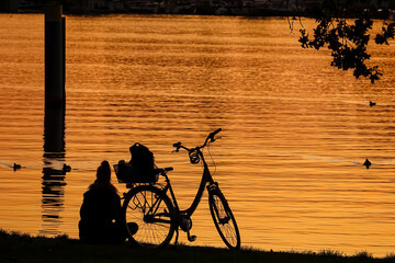 Frau mit Fahrrad am See bei Sonnenuntergang