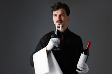Professional sommelier tasting red wine on gray background