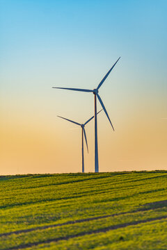 Wind Turbines At Golden Hour Over Green Hills Near Bourscheid, Luxembourg