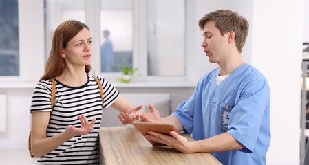 Fototapeta premium Medical assistant helping patient at reception in clinic