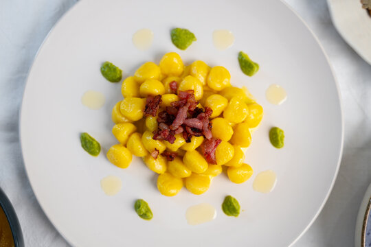 Italian pumpkin gnocchi with crispy bacon and pesto drops, gourmet plated dish