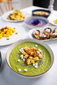 Italian Green Vegetable Soup with Croutons and Gourmet Plating on White Table