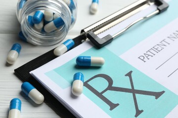 Medical prescription form with empty fields and pills on white wooden table, closeup