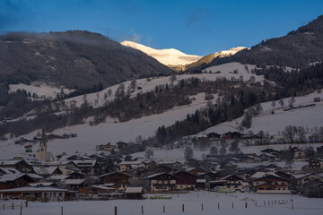 beautiful view of the snow capped mountains in the hohe tauern in austria over a village, at a sunny cold winter morning