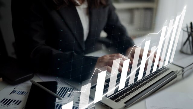 A professional businesswoman works intently on a laptop, analyzing financial data with a stylish graph overlay in a sleek modern office environment. Copula - Powered by Adobe