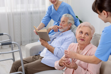 Fototapeta premium Care workers helping senior man and woman at retirement home, closeup