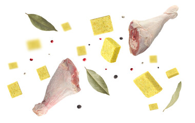Bouillon cubes, chicken drumsticks, dry bay leaves and peppercorns flying in air on white background