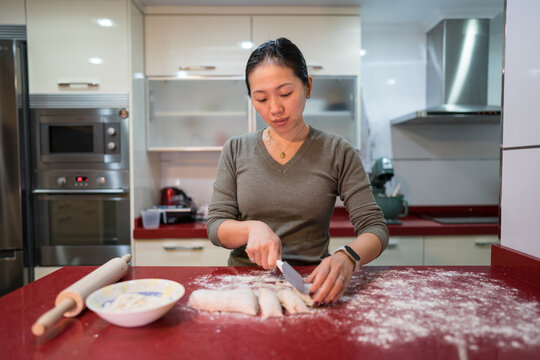 Woman slicing homemade pita dough in a modern kitchen