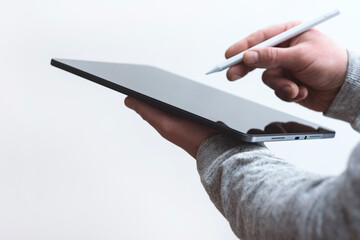 Close up of man holding digital tablet in one hand and stylus pen in the other against clean white background. Concept for technology, design and productivity work.