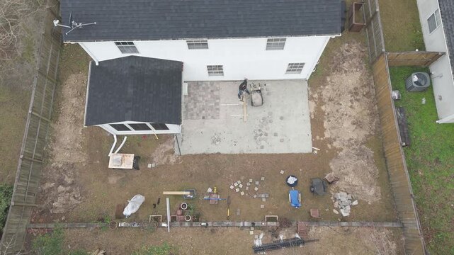 Overhead drone shots of man working on his backyard paver patio doing a DIY construction project. 