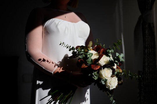 Bride holding elegant bouquet in soft shadow