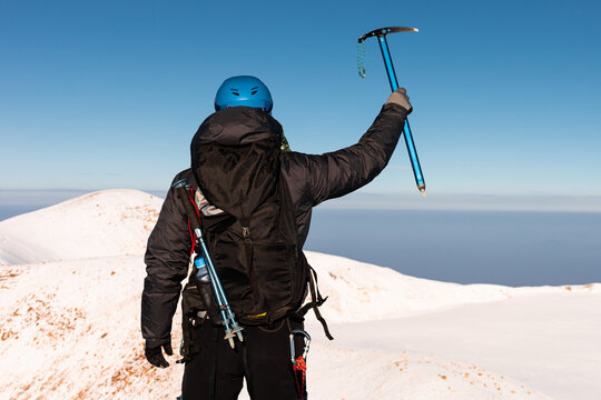 Alpinist with gear ascending snowy volcano summit