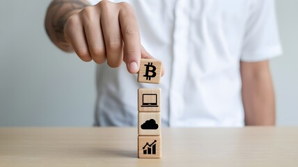 Person in White Shirt Stacking Wooden Blocks with Bitcoin, Laptop, Cloud, and Graph Symbols on a Wooden Table
