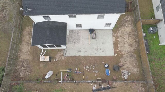Overhead drone shots of man working on his backyard paver patio doing a DIY construction project. 