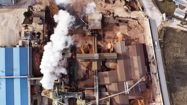 Aerial view of the onga board factory. White smoke rising from the chimneys, piles of raw materials