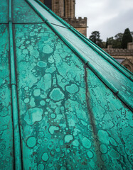Verdigris-Covered Architectural Surface with Textured Details Against Cloudy Skies