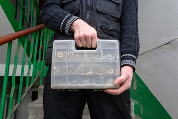 master holds a transparent plastic organizer for hardware in front of him