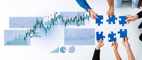 Business professionals collaborate on strategy using puzzle pieces and data visuals on a clean surface, highlighting teamwork in financial growth and metrics analysis. Scalp