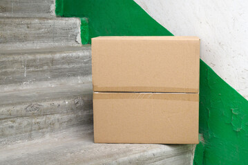 closed brown cardboard box on concrete steps in a house entrance hallway