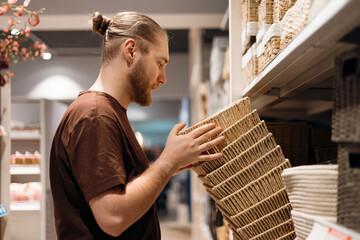 Young man selecting an eco woven basket in a home goods store, sustainable.