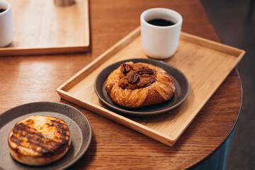Fresh apple pastry served with black coffee on wooden tray in cafe.