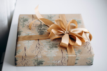 Eco-friendly gift wrapped in kraft paper with gold ribbon bow.