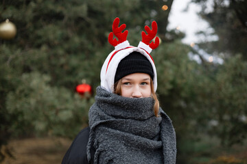 Teen girl portrait outdoors wearing reindeer antler headband, festive look.