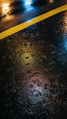 Wet asphalt road texture with yellow line and city light reflections