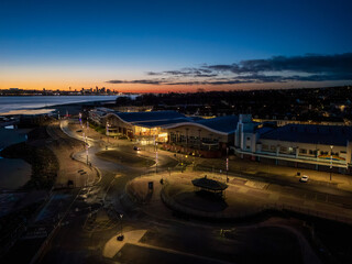 Fototapeta premium An aerial view captures the dawn over New Brighton, Wirral, with the Floral Pavilion Theatre and Liverpool skyline visible.