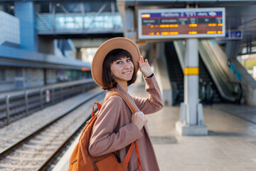 Girl with a backpack. portrait of a beautiful and young girl in a hat at the station. A young woman in a coat and hat is standing on the station platform.