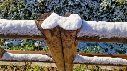 Snow covering rustic wooden fence in winter garden
