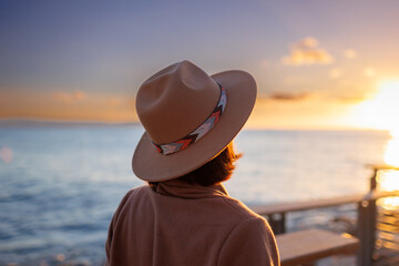 girl looks at the sea. stylish and beautiful young woman in a coat and hat looks at the sea. Walk along the beach.