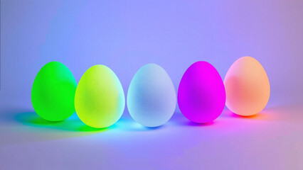 F&uuml;nf leuchtende Neon Ostereier in einer Reihe mit farbiger Beleuchtung