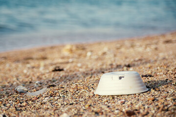 Plastic foam cups, and various garbage scattered on the sand at the seaside. Environmental pollution and marine debris problem.