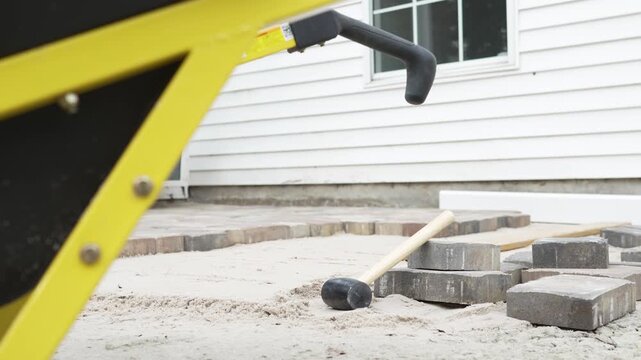 Details of rubber hammer, wheelbarrow, patio pavers, and sand 