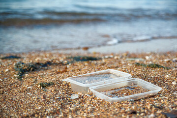 Plastic containers and various garbage scattered on the sand at the seaside. Environmental pollution and marine debris problem.