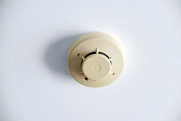 Fire alarm smoke detector installed on a white ceiling for home safety and fire prevention. System for detecting smoke in building.