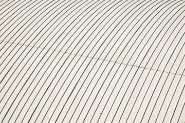 High angle view of a white corrugated metal sheet roof. Minimalist industrial texture and repetitive pattern background.