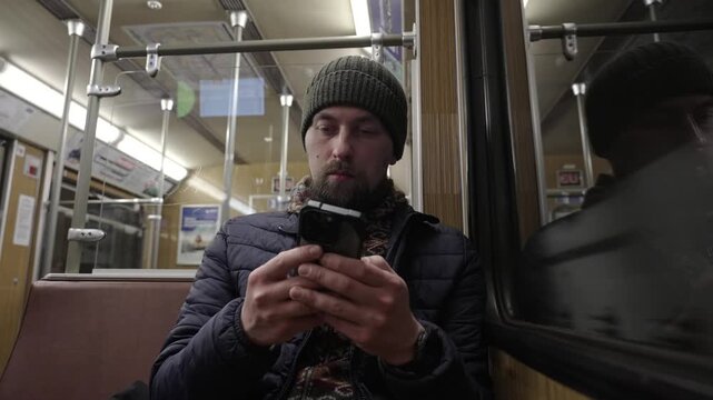A passenger sits by the window of an old Muenchen U-Bahn train, using his phone. Vintage transit experience in Bavaria featuring historic wood design and classic carriage style.