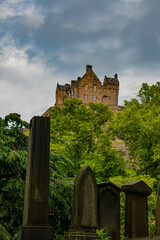 Edinburgh, Scotland, Uk: ancient tombstones in the graveyard of the Scottish Episcopal St John's Church, Princes Street, with Edinburgh Castle on Castle Rock in the background