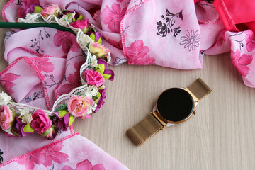 Women's smartwatch with a gold metal band and a flower tiara on a wooden backgorund. Ideal for fashion accessories, beauty branding, lifestyle content, and modern feminine technology concepts.