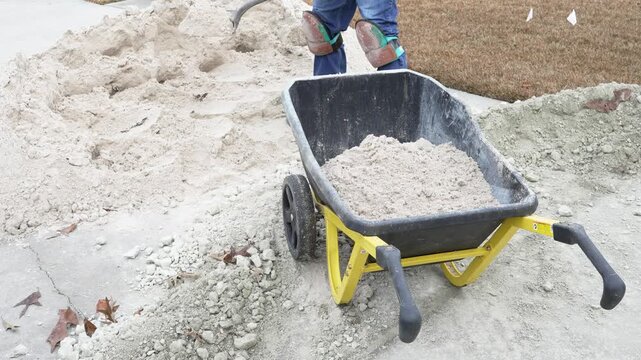 Man shoveling sand into wheelbarrow for DIY project at his home