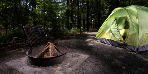 Bright dome tent in a forested campsite with a lake in the distance