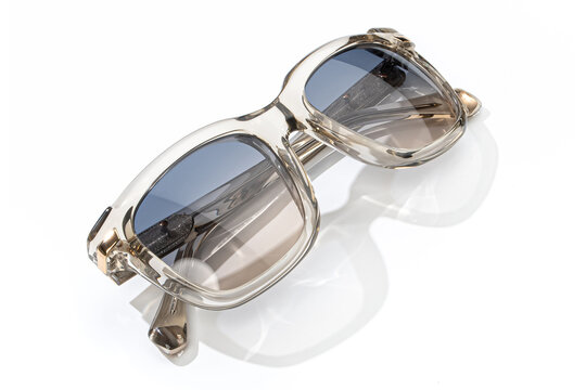 Sunglasses in gray smoke bright color in transparent plastic. Eyewear folded top view with shadow. Trendy sunglasses isolated on white background. Fashion glasses for women with blue shade polarized