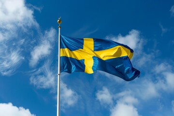 Swedish flag waving against blue sky with some clouds