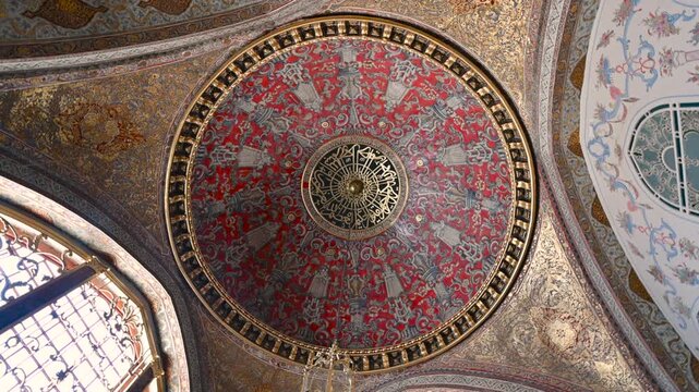 Istanbul, Turkey, August 1, 2025. Majestic view upward at ornate ottoman mosque dome with gilded patterns, arabic calligraphy and sunlight through arched windows. Rotation movement.
