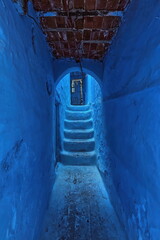 Narrow passageway in the medina under a brick and beam framework supporting houses, painted as is customary in shades of blue. Chefchaouen-Morocco-023