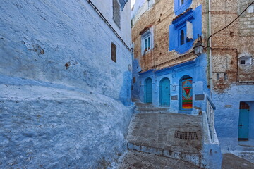 Sloping and stepped street in the blue-painted medina featuring three ornate wood doors, studded and colorfully painted. Chefchaouen-Morocco-032