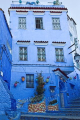Traditional three-story house in a well-known alley in the medina painted in shades of blue, with colorful planters and pots. Chefchaouen-Morocco-038