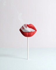 Shiny red lollipop mouth blowing out cigarette smoke, creative aesthetic concept.